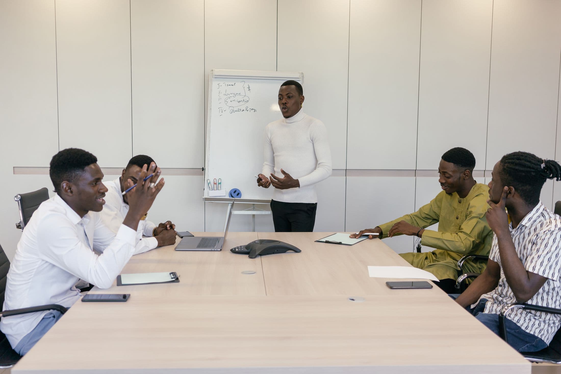 A team of professionals in a working session, one of them presenting at a whiteboard